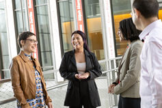 Four smiling individuals talk to one another in the lobby of the Global and International Studies building.